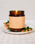 Gros plan sur le coffret cadeau bougies Collection Fruitée parfum Pêche avec pot en verre ambré et flamme éclatante