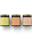 Coffret cadeau bougies Collection Fruitée avec trois pots en verre ambre et couvercles dorés, étiquettes pastel délicates