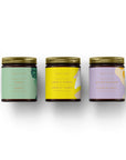 Coffret cadeau bougies Collection Rêverie dans pots en verre foncé avec couvercles dorés sur fond blanc