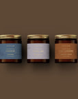 Gros plan sur le coffret cadeau bougies Altrum Collection Épicée, bocaux en verre ambré et couvercles dorés cannelés