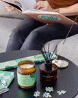 Hinoki fragrance set reed diffuser in amber glass with black matte cap on round black wood table