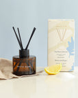 Close-up of Northern Breeze Fragrance Set's amber glass reed diffuser with black reeds and matte cream-blue packaging