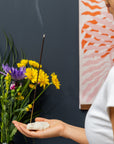 Gros plan sur Bâtons d'encens Fleur de saule dans un support pierreux naturel avec une fumée blanche délicate