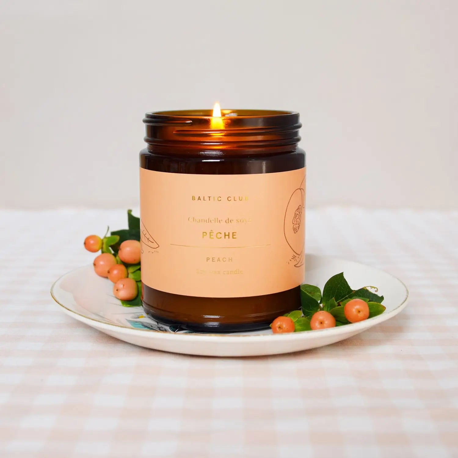 Peach Baltic Club Soy Candle burning on a table cloth