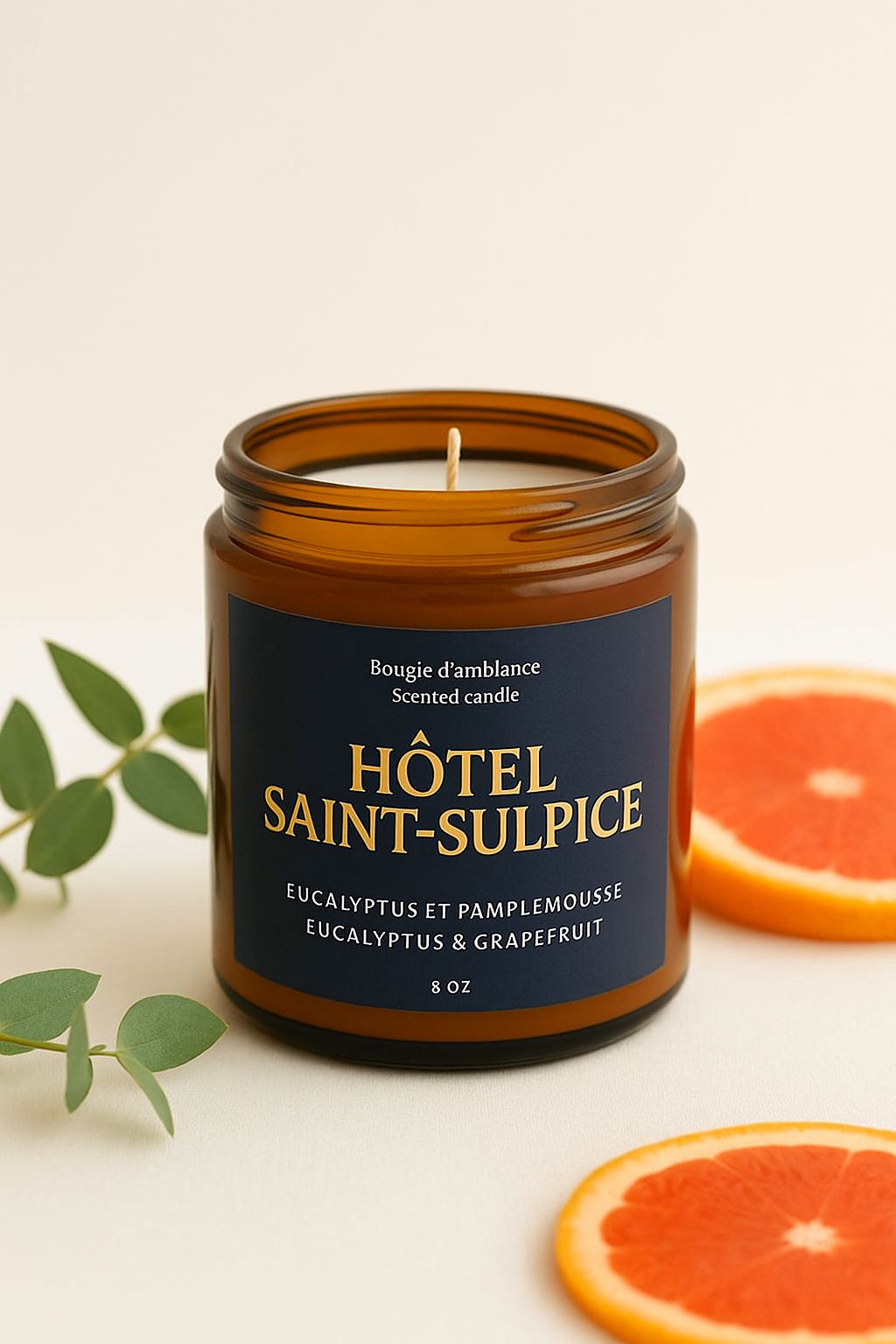 Scented candle labeled 'Hotel Saint-Sulpice' with grapefruit slices and leaves on a beige background