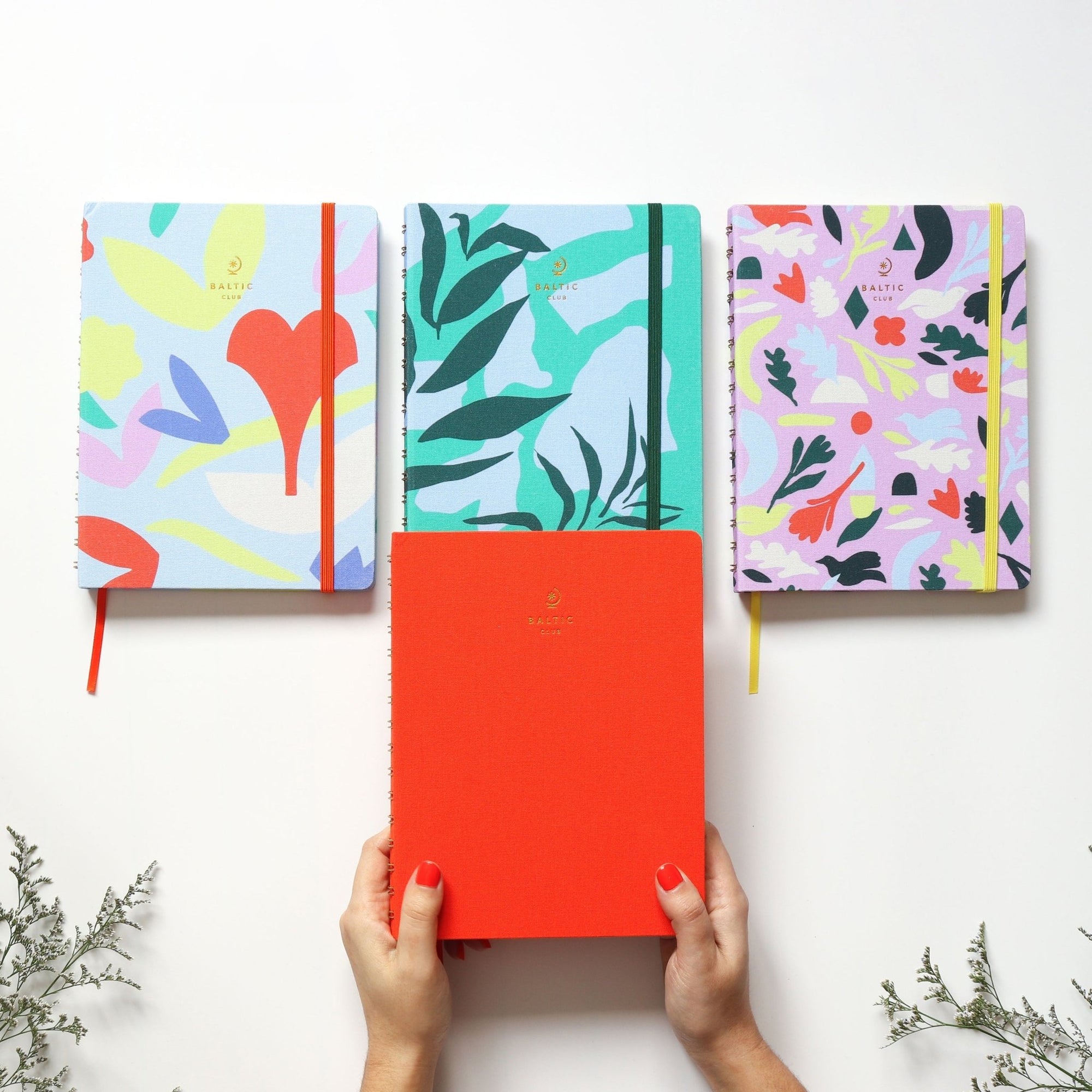 Gros plan sur la reliure spirale du carnet Bouquet avec élastique rouge et couverture abstraite vibrante