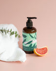 Elegant hand soap bottle with eucalyptus and grapefruit accents on soft pastel pink background