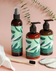 Amber bottles of Baltic Club eucalyptus and grapefruit scented hand care products with fresh eucalyptus leaves on soft pink background
