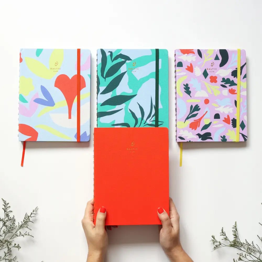 Gros plan sur l'agenda non daté Jardin avec reliure spirale, élastique de fermeture et logo doré Baltic Club sur couverture colorée