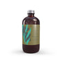Sea Grass reed diffuser refill in a glossy amber glass bottle reflecting soft studio light