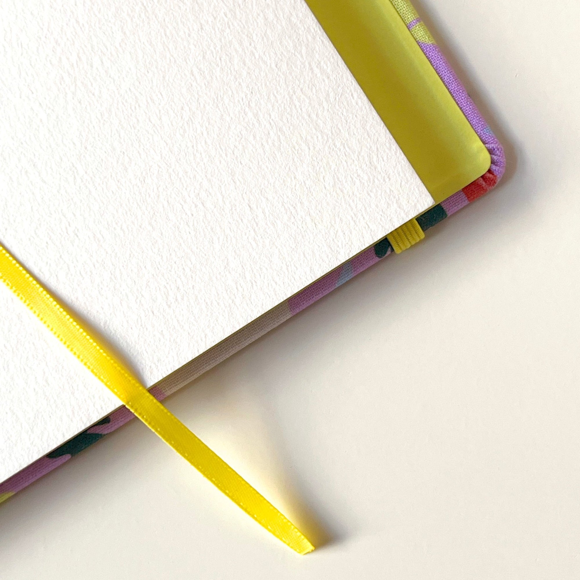 Vue plongeante inclinée du carnet à dessins Murmure ouvert sur une page vierge, dévoilant sa couverture rigide et sa reliure cousue.