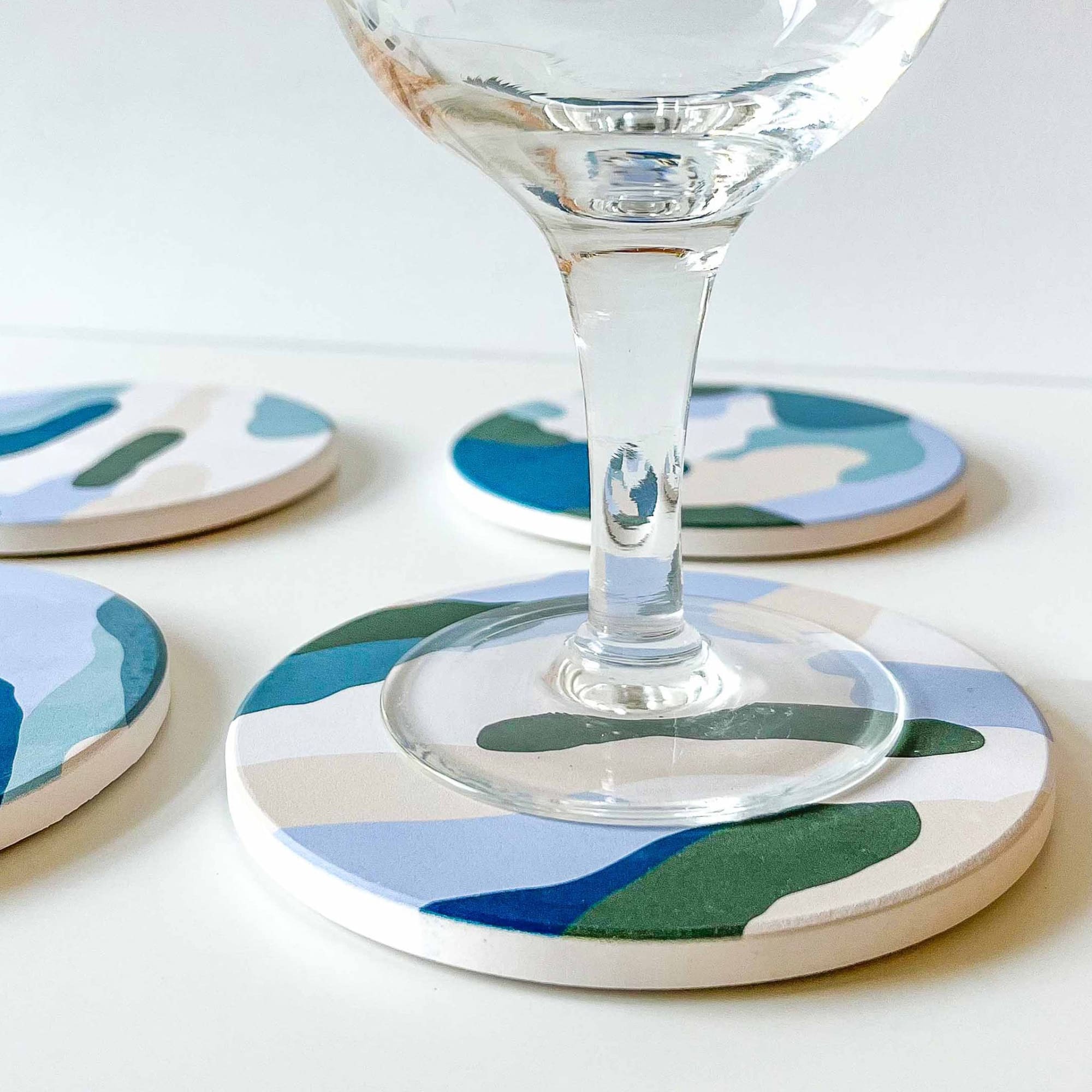Set of absorbent ceramic coasters with an empty glass on one of them