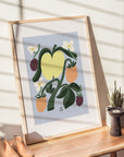 The Apple Art print from artist Lotta Maija, for the Baltic Club, in its frame on a table at dawn